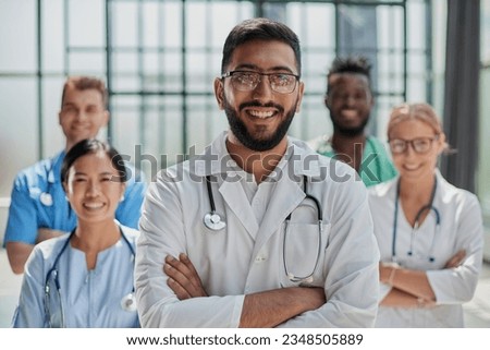 Successful team of medical doctors are looking at camera and smiling while standing in hospital