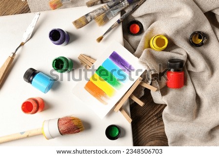 Canvas with brushes, paints and cloth on brown wooden table