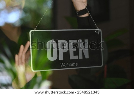 Man coffee shop or restaurant owner turning Open sign on the entrance door.