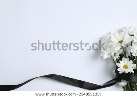 Beautiful chrysanthemum flowers and black ribbon on white background, top view with space for text. Funeral symbols Royalty-Free Stock Photo #2348531339