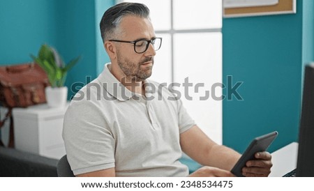 Grey-haired man business worker using touchpad thinking at the office