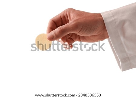 Detail of the hand of a priest in communion with a host consecrated as the body of Christ with a white isolated background