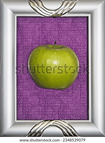 A green apple inside a silver photo frame