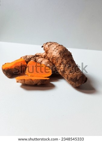 close-up of bunch of fresh whole and sliced ​​turmeric isolated on white background.