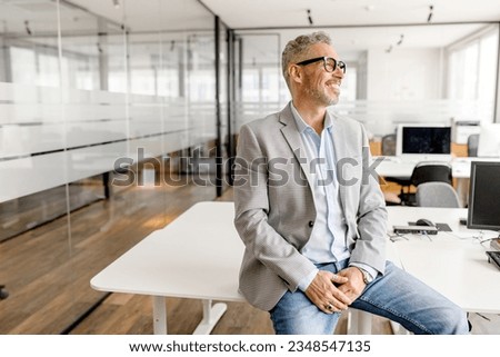 Serene modern middle aged businessman in formal wear leaned on the desk looking away, inspired and calm mature business owner at the office, confident grey-haired man in relaxed pose Royalty-Free Stock Photo #2348547135