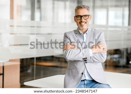 Cheerful mature 50s businessman, startup owner, investor standing with arms crossed in his office. Mature proud gray-haired male boss, ceo, professional in formal wear looking at camera and smiling Royalty-Free Stock Photo #2348547147