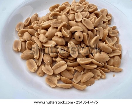 a photography of a plate of peanuts on a table, china cabinet of peanuts on a plate. Royalty-Free Stock Photo #2348547475