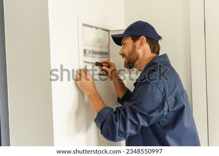 Smiling male electrician inspect and repairing electrical systems in houses and buildings Royalty-Free Stock Photo #2348550997