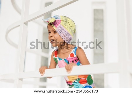 Funny cute girl on summer vacation. The child has fun near the pool. Cute baby girl in a colorful swimsuit is resting.