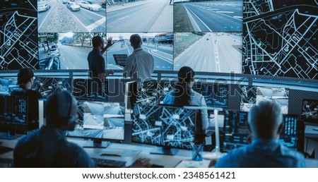 High-Tech International Logistics Office with Multiethnic Specialists Using Satellite Technology to Track a Fleet of Delivery Vehicles on a City Map. Large Display Shows Real-Time CCTV Feed and Report Royalty-Free Stock Photo #2348561421