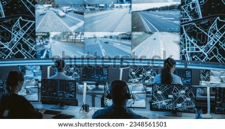 Dark Monitoring Room with Multiethnic Specialists Monitoring Surveillance Feeds and Coordinating Traffic Operations on Desktop Computers. Employees Working in High-Tech Office with Multiple Screens Royalty-Free Stock Photo #2348561501