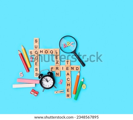 back to school concept. wooden alphabet letters and supplies on abstract blue background. symbol of education, Knowledge Day. wooden letters of school theme crossword words. flat lay. copy space