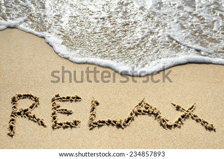 relax word written on sandy beach near sea - holiday concept