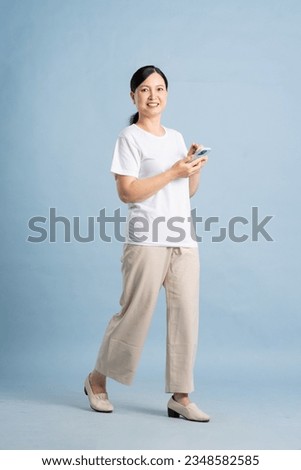 full body photo of an elderly woman using a smartphone