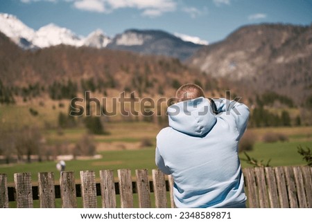 Photographer with a camera taking a picture of the snow mountains against blue sky in the Alps. Wanderlust concept.
