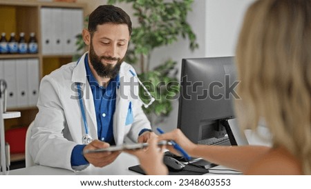 Young hispanic man doctor giving contract to patient to sign at the clinic