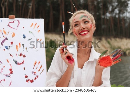 Portrait of Happy pretty artist woman with hands painted in the park. Creative design. Creative Expression consept. Talanted female is showing colorful paintes hands. She is smiling. Modern art.