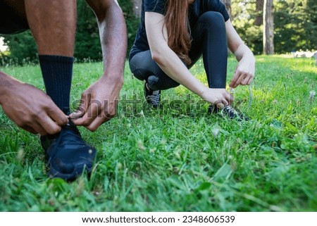Close-up of the hands of two sportspeople tying their shoes, photo with copy space