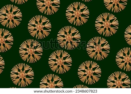 Christmas pattern of ethnic straw snowflakes on a green background