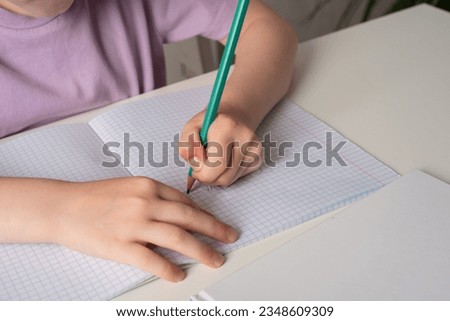 Close-up of children's hands. Left-hander writes in a notebook on the table. International Left Handers Awareness Day Royalty-Free Stock Photo #2348609309