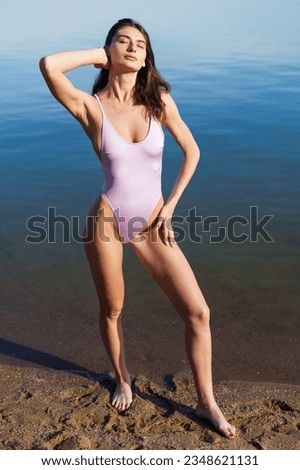 A young woman poses in a swimsuit outside. Model sunbathing on the beach.
