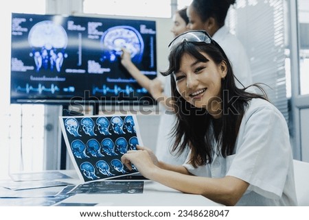 Team of female doctor check on scan results paper and looking at monitors in laboratory, share medical knowledge and experience benefits her coworkers and patients before surgery and treatment