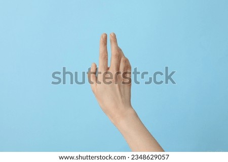 Female well-groomed hand on a light blue background