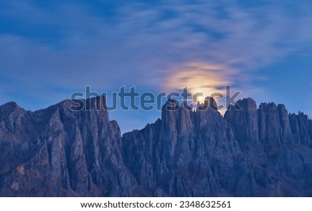 Night photo of Mount Latemar, the moon rises over the mountain range of Bolzano province, South tyrol, Italy