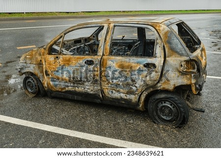 Side view of a burnt and abandoned rusty van and a broken headlight. Burned out car in street. The skeleton of a burnt car. Shallow depth of field Royalty-Free Stock Photo #2348639621