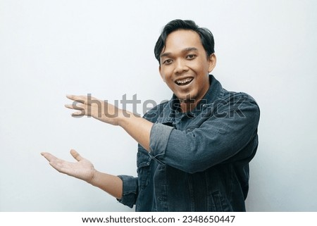 Young Asian man smiling while put hand palms in side of his body for presenting something