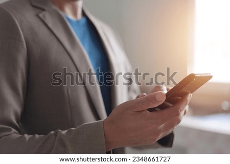 Closeup of adult male hand using mobile phone, Young man texting on smartphone over grey background.