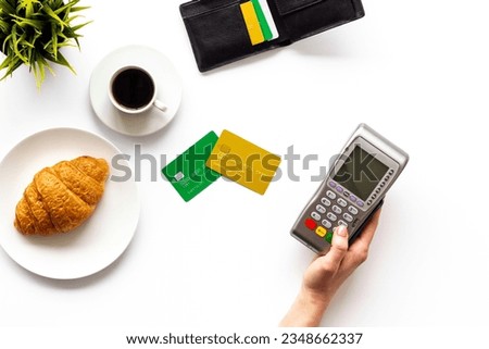 Payment by credit card for coffee and croissant. Pos payment terminal with wallet.
