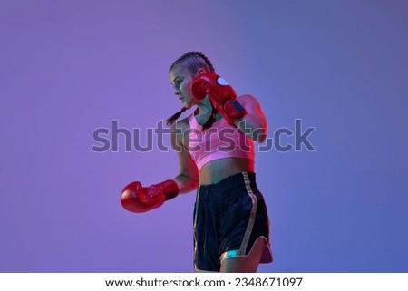 Teen athletic girl, MMA fighter in motion, training kicks against purple studio background in neon lights. Concept of mixed martial arts, sport, hobby, competition, athleticism, strength, ad