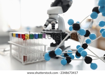 There is rack on table with many test tube with colorful lid and plastic molecule. Royalty-Free Stock Photo #2348673417