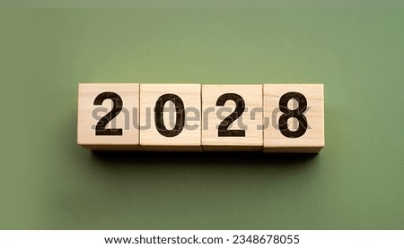 2028 displayed on wooden letter blocks on Olive color background.