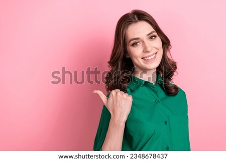 Photo of excited pretty woman dressed green shirt showing thumb back empty space isolated pink color background