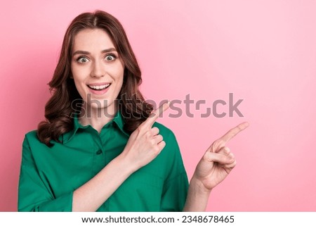 Photo of cheerful excited woman dressed green shirt open mouth showing two fingers empty space isolated pink color background