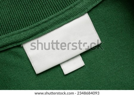 Blank white laundry care clothes label on green shirt fabric texture background Royalty-Free Stock Photo #2348684093