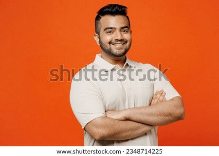 Side view young smiling happy cheerful Indian man he wears white t-shirt casual clothes hold hands crossed folded look camera isolated on plain orange red background studio portrait. Lifestyle concept Royalty-Free Stock Photo #2348714225