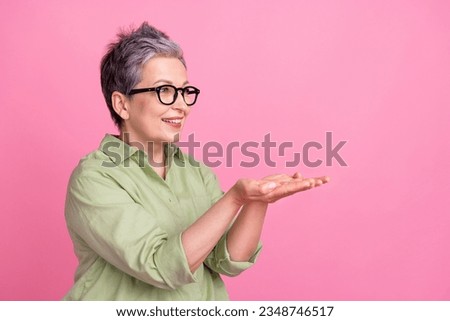 Photo of attractive retired businesswoman wear stylish shirt holding arms presentation object empty space isolated on pink color background