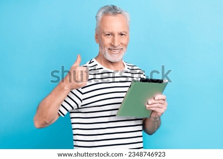 Photo portrait of handsome grandad hold tablet showing thumb up dressed stylish striped clothes isolated on blue color background