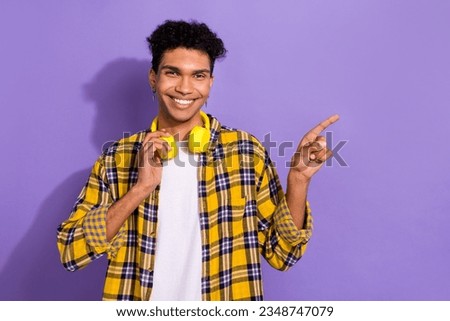 Photo of cool funky guy dressed checkered yellow shirt headphones showing finger empty space isolated purple color background