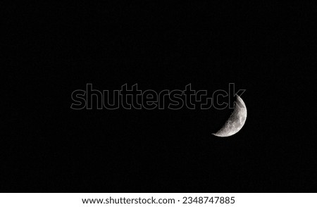 Half moon covered with shadow in the black sky.
