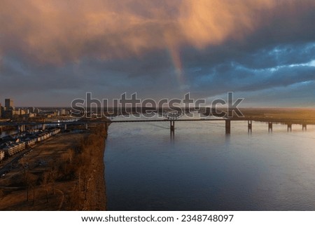 aerial shot of the waters of the Mississippi River with Hernando do Soto Bridge over the water and office buildings, homes and apartments along the banks with blue sky clouds and a rainbow in Memphis