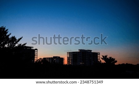 Fragment of modern residential building on dawn background with sun and clouds.