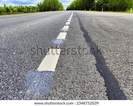 White dotted line on grey asphalt road background. Track in nature and summer landscape
