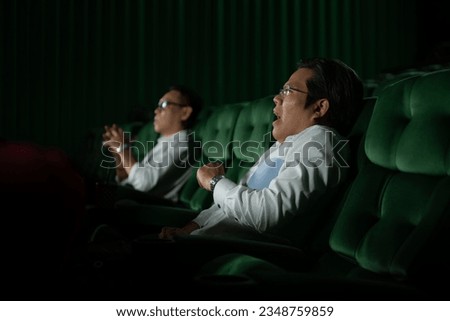 Young couple watching movie in cinema, sitting on the green seats.