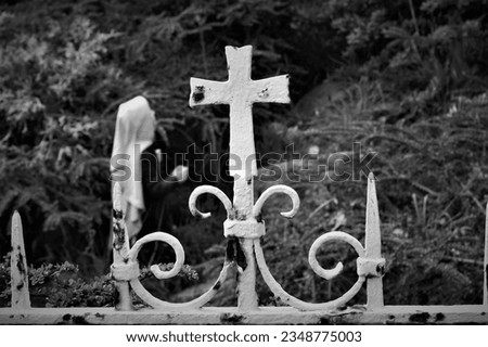 A fragment of an old metal fence. Old metal fence with a cross near the church. Black and white image.