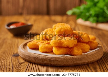 Portion of freshly cooked homemade nuggets in a wooden plate. Studio shot from a low angle. Royalty-Free Stock Photo #2348775731