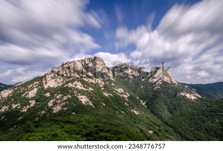 Mountains in Bukhansan National Park during day. Photo was taken with long exposure, as result of that clouds a blurred and movement of them is visible. Royalty-Free Stock Photo #2348776757